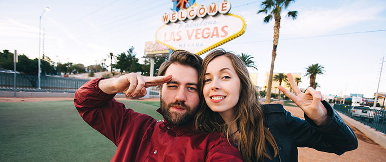 Man and woman posing in front of the Welcome to Fabulous Las Vegas sign